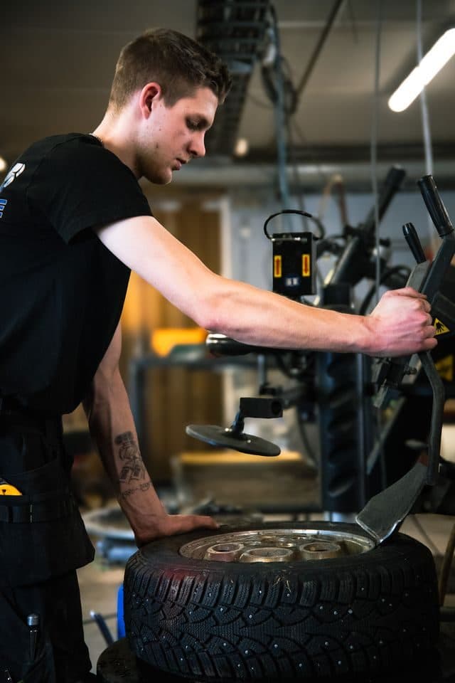 Mekaniker legger om piggdekk på dekkmaskinen